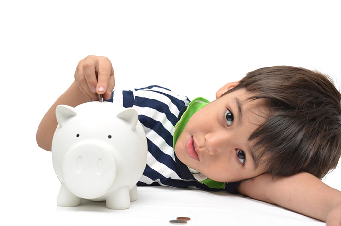 Little boy saving money in piggy bank